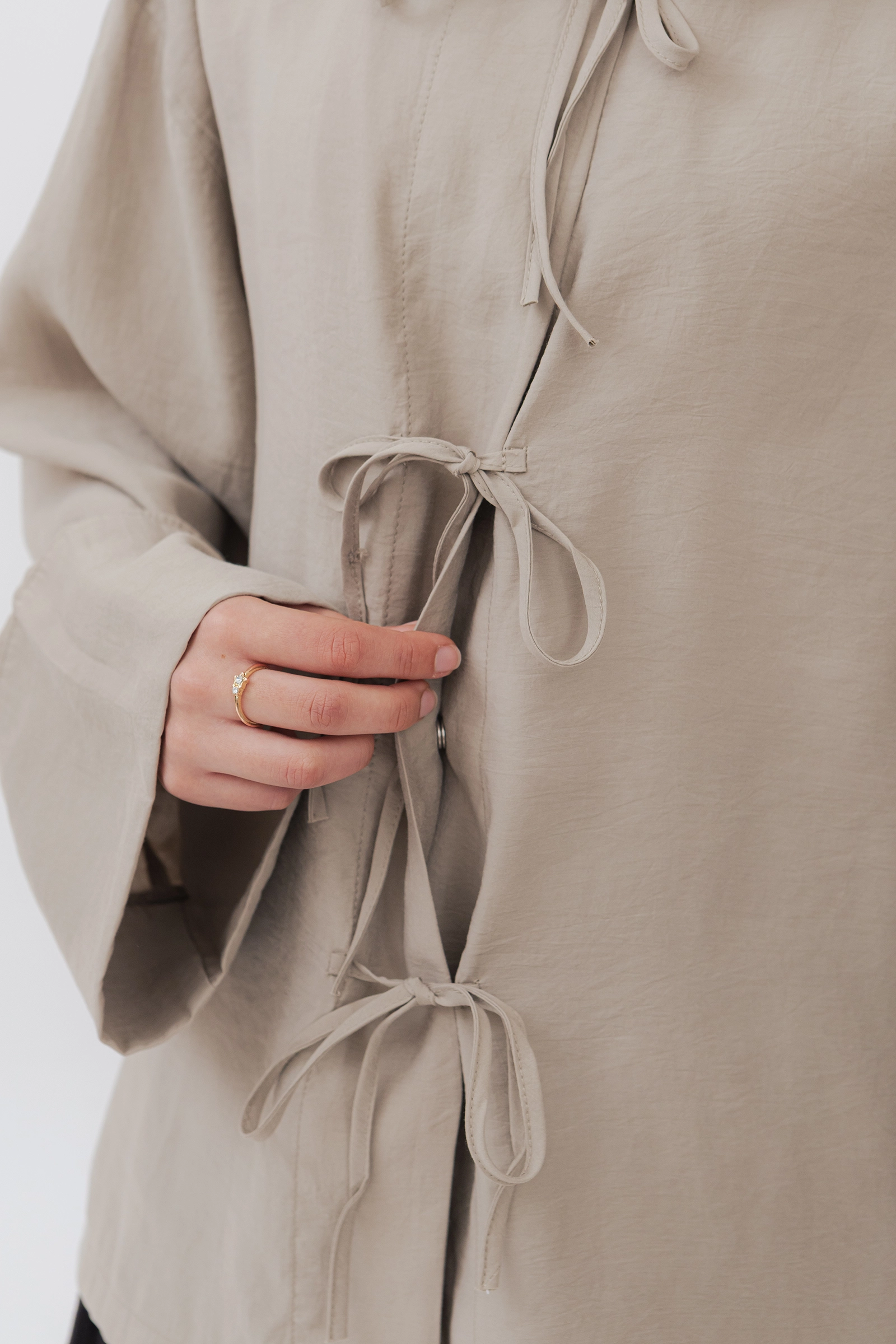 Detalle del lazos y broches ocultos de la blusa modesta de modal en beige piedra