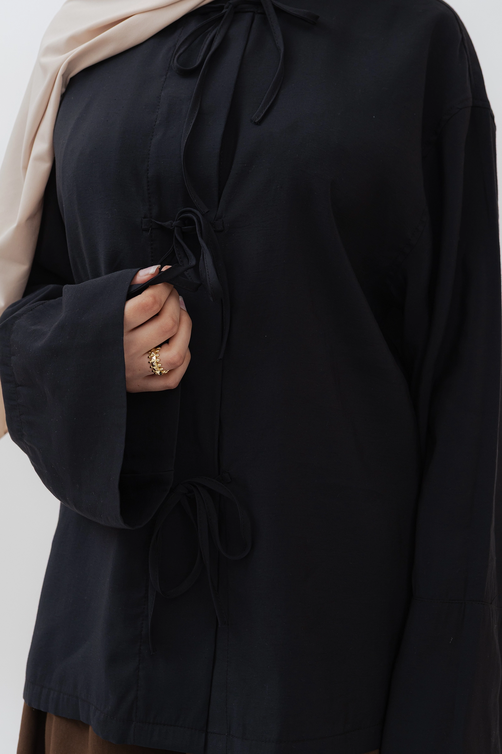 Detalle del los tres lazos frontales de la blusa modesta de modal con manga larga en negro