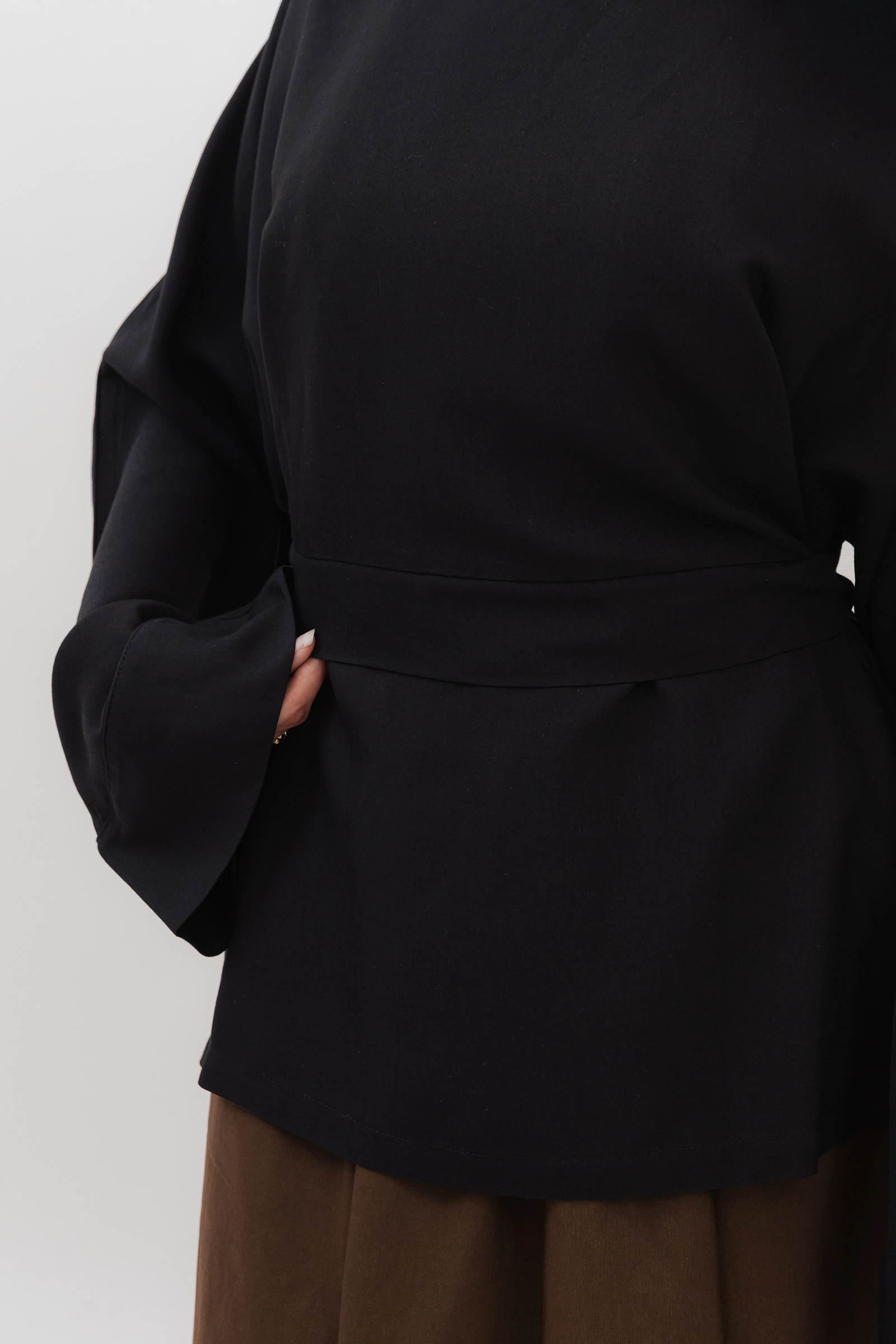 Detalle de cintura y manga de la túnica modesta negra con lazo, tejido Tencel